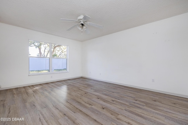 empty room with a ceiling fan, wood finished floors, baseboards, and a textured ceiling