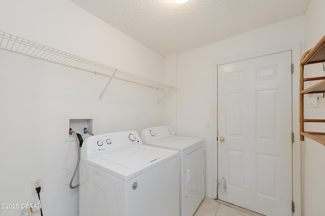 clothes washing area featuring laundry area, light tile patterned floors, separate washer and dryer, and a textured ceiling