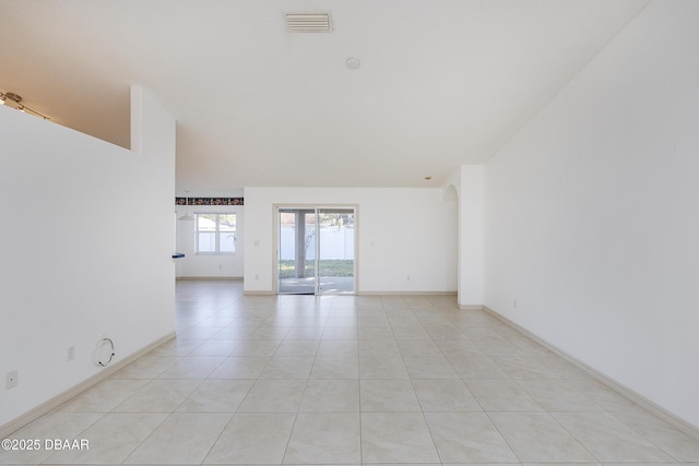 spare room featuring light tile patterned floors, visible vents, and baseboards