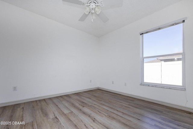 empty room featuring light wood finished floors, baseboards, and ceiling fan