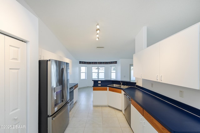 kitchen featuring light tile patterned floors, a peninsula, a sink, stainless steel appliances, and white cabinets