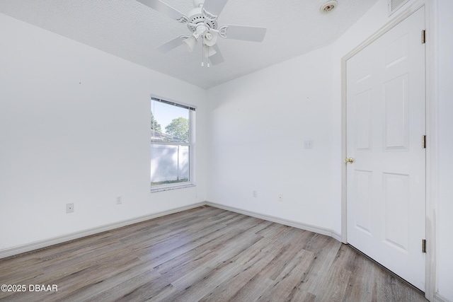 spare room featuring light wood-style flooring, a textured ceiling, baseboards, and a ceiling fan