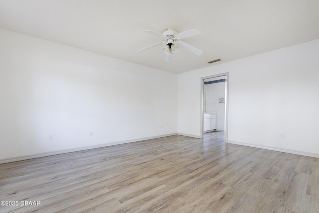 empty room featuring baseboards, visible vents, a ceiling fan, and light wood-style floors