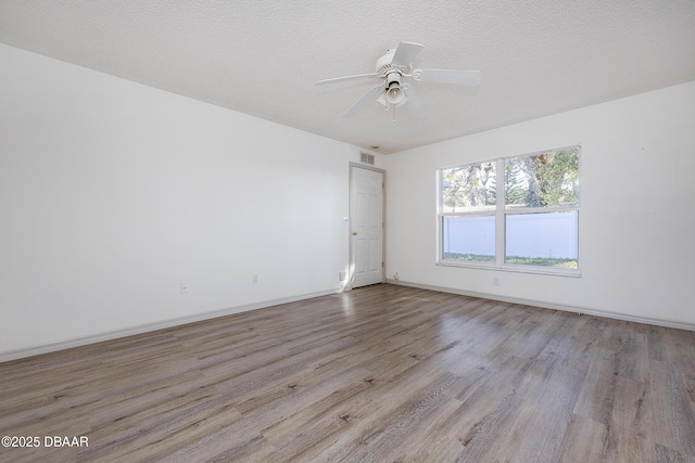 spare room featuring ceiling fan, baseboards, a textured ceiling, and wood finished floors