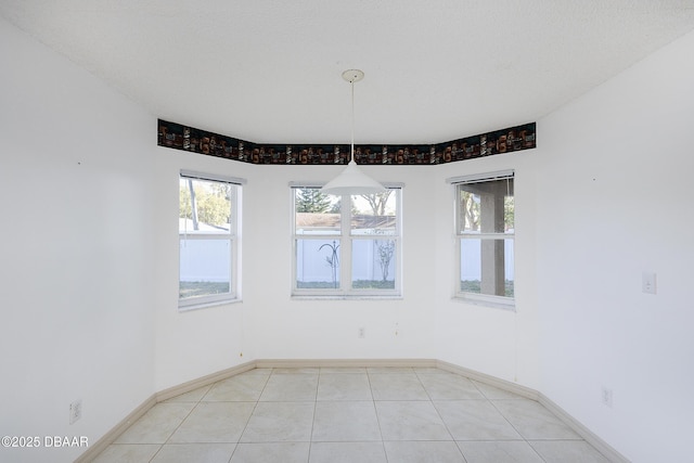 spare room featuring light tile patterned floors and baseboards