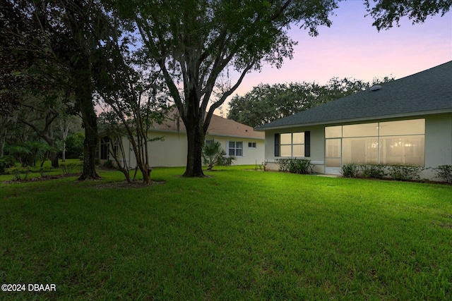 back house at dusk featuring a yard