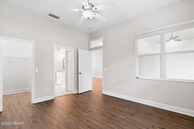 unfurnished bedroom featuring ceiling fan, a closet, dark wood-type flooring, and a spacious closet