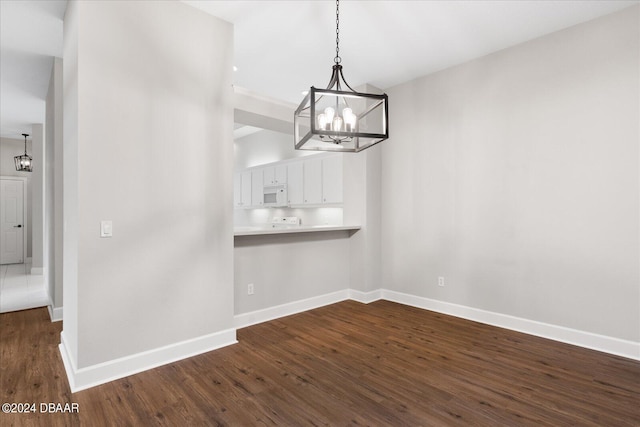 unfurnished dining area featuring a chandelier and dark hardwood / wood-style floors