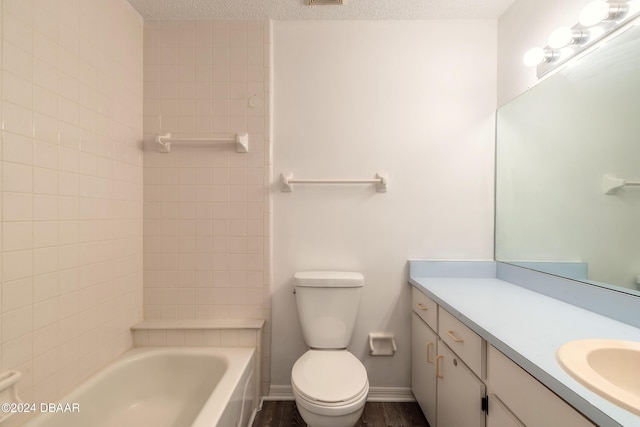 full bathroom with toilet, a textured ceiling, tiled shower / bath, and vanity