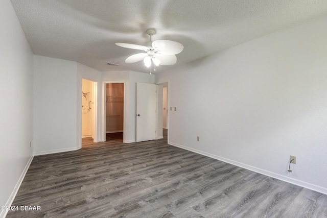 unfurnished bedroom featuring a textured ceiling, a spacious closet, ceiling fan, wood-type flooring, and a closet