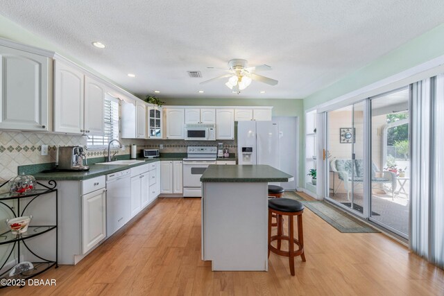 3167 S Peninsula Dr, Daytona Beach, FL 32118 - kitchen with visible vents, a breakfast bar, a sink, dark countertops, and white appliances
