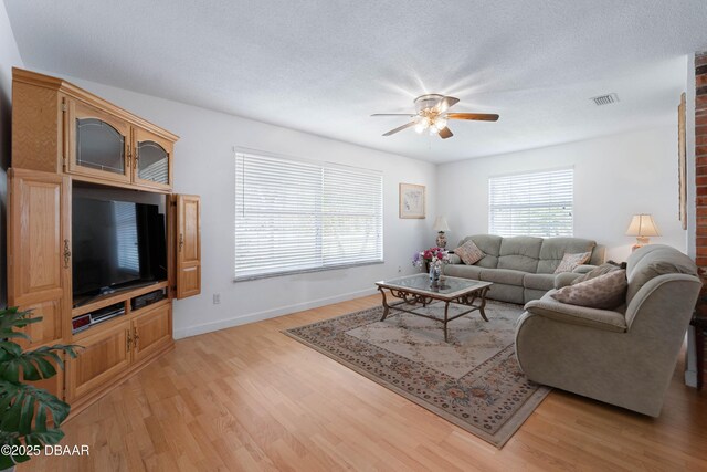 3167 S Peninsula Dr, Daytona Beach, FL 32118 - living room featuring visible vents, baseboards, ceiling fan, light wood-style flooring, and a textured ceiling