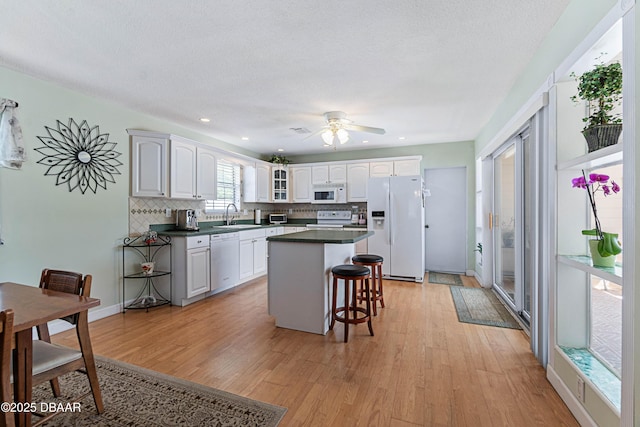 3167 S Peninsula Dr, Daytona Beach, FL 32118 - kitchen with backsplash, a kitchen island, a breakfast bar area, light wood-style flooring, and white appliances