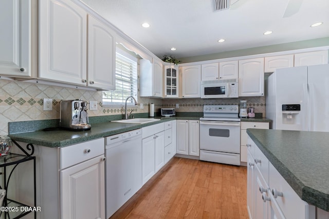 3167 S Peninsula Dr, Daytona Beach, FL 32118 - kitchen with dark countertops, visible vents, white cabinets, white appliances, and a sink
