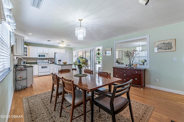 3167 S Peninsula Dr, Daytona Beach, FL 32118 - dining area with visible vents, baseboards, light wood-style floors, and ceiling fan with notable chandelier