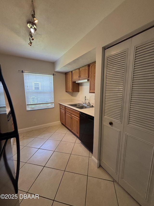 917 Royal Oak Ct, Holly Hill, FL 32117 - kitchen featuring black dishwasher, light countertops, light tile patterned flooring, rail lighting, and brown cabinetry