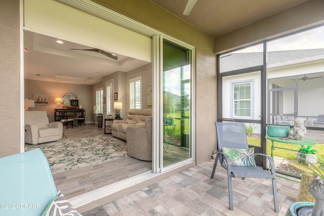 sunroom with ceiling fan and a tray ceiling