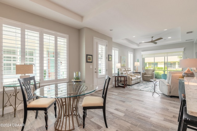 dining space featuring a wealth of natural light, ceiling fan, light hardwood / wood-style flooring, and a tray ceiling