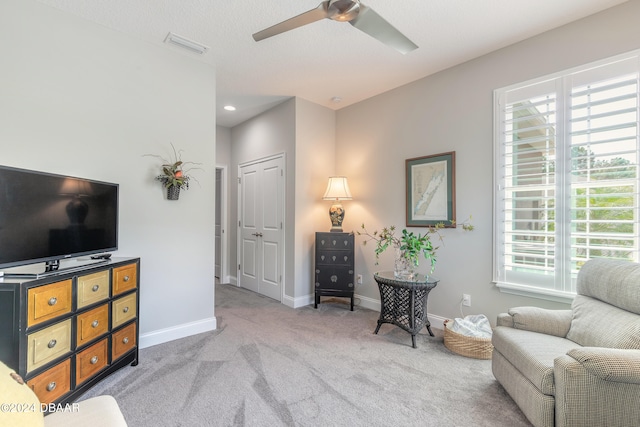 sitting room featuring a wealth of natural light, ceiling fan, a textured ceiling, and light colored carpet