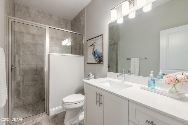 bathroom with hardwood / wood-style flooring, vanity, toilet, and walk in shower