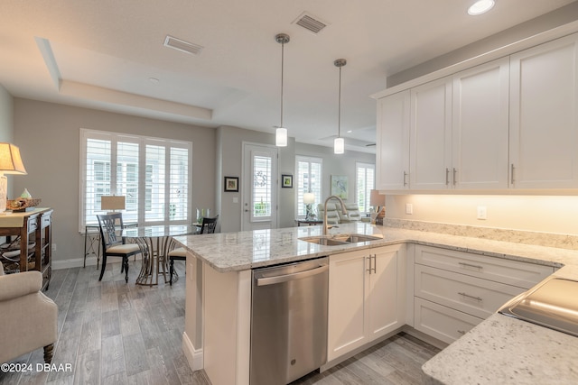 kitchen with light hardwood / wood-style floors, sink, kitchen peninsula, stainless steel dishwasher, and pendant lighting