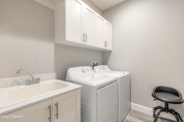 laundry room with cabinets, light hardwood / wood-style flooring, sink, and washer and dryer