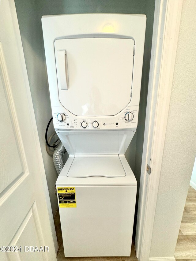 clothes washing area featuring stacked washing maching and dryer and light hardwood / wood-style flooring