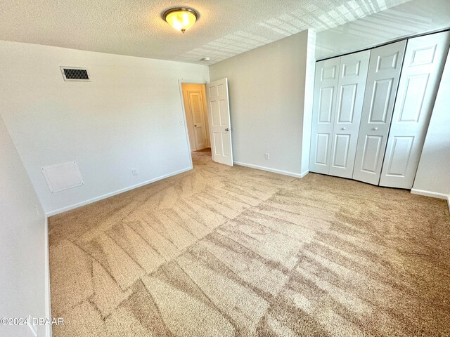 unfurnished bedroom featuring a textured ceiling, a closet, and carpet