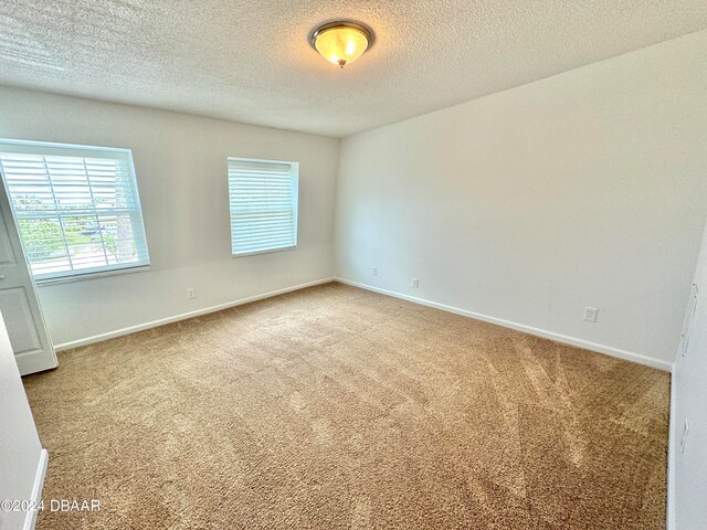 unfurnished room featuring a textured ceiling and carpet floors