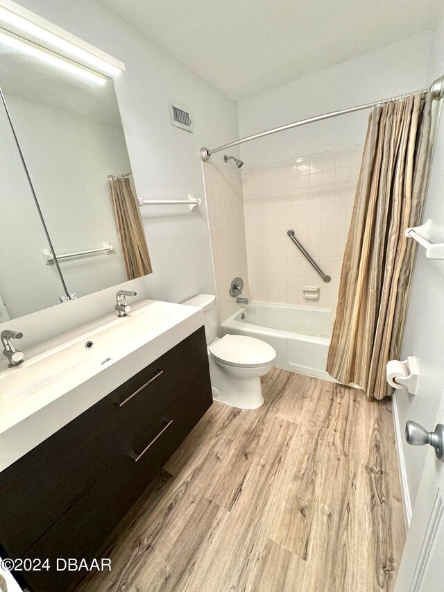 full bathroom featuring hardwood / wood-style flooring, vanity, toilet, and shower / bathtub combination with curtain