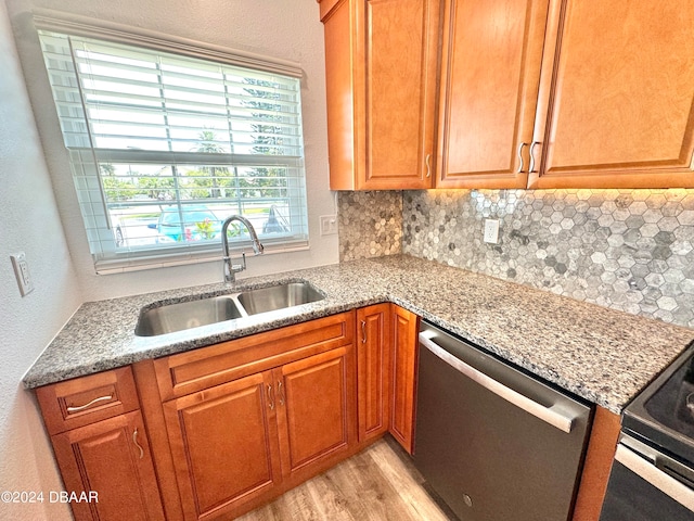 kitchen featuring light stone counters, dishwasher, sink, backsplash, and light wood-type flooring