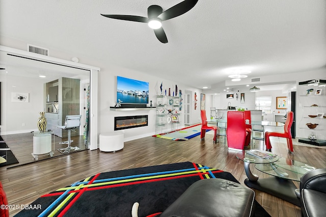 living room featuring ceiling fan, hardwood / wood-style floors, and a textured ceiling