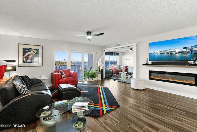 living room featuring ceiling fan, dark wood-type flooring, and a textured ceiling