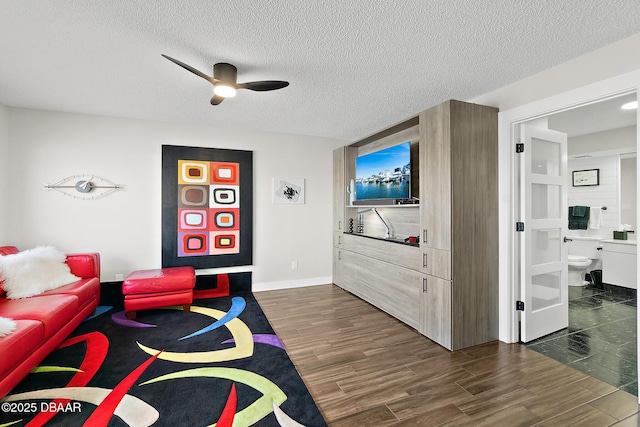 living room with dark wood-type flooring, ceiling fan, and a textured ceiling