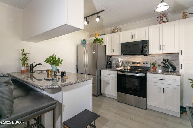 kitchen featuring backsplash, a breakfast bar, ornamental molding, stainless steel appliances, and white cabinetry