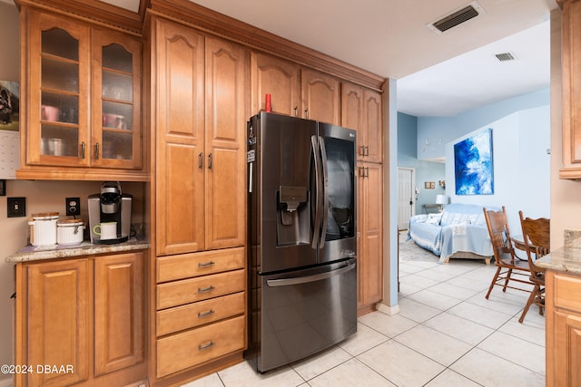 kitchen with light tile patterned flooring, light stone counters, and stainless steel fridge