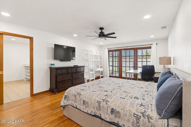 bedroom with light wood-type flooring, ceiling fan, and ensuite bath