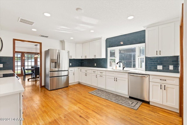 kitchen featuring stainless steel appliances, white cabinets, sink, and light wood-type flooring