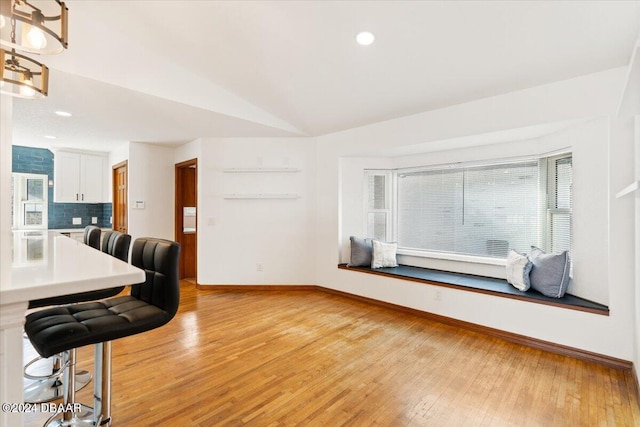 living room featuring light wood-type flooring and vaulted ceiling