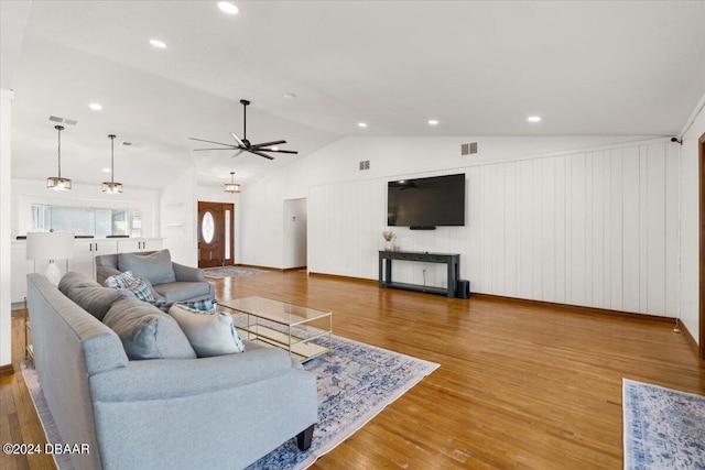 living room featuring hardwood / wood-style floors, wood walls, ceiling fan, and vaulted ceiling