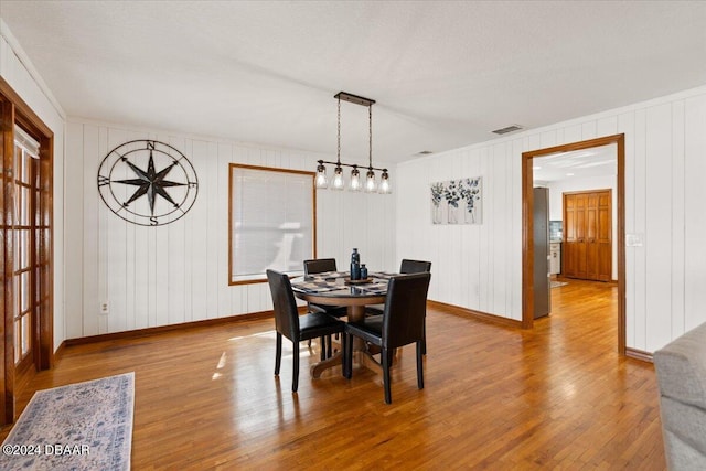 dining room featuring light hardwood / wood-style flooring and wooden walls