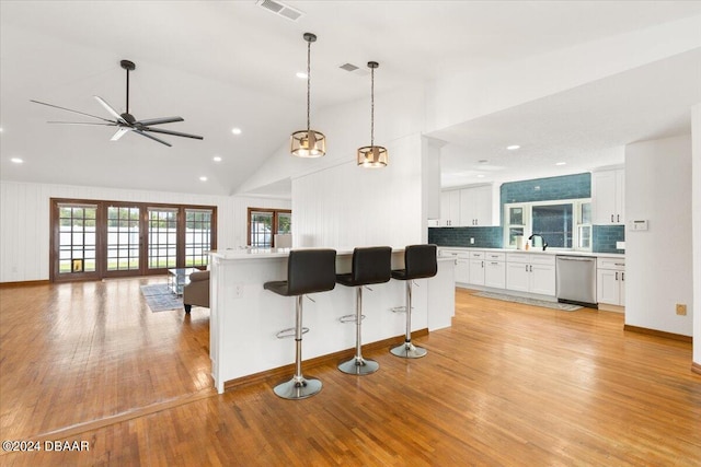 kitchen featuring white cabinets, light wood-type flooring, stainless steel dishwasher, and a kitchen island