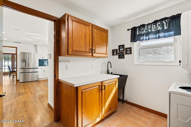 kitchen featuring light hardwood / wood-style flooring, washer / clothes dryer, and stainless steel fridge with ice dispenser