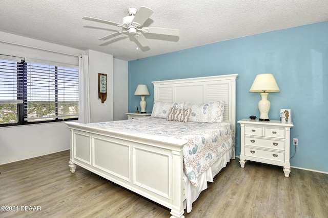 bedroom featuring hardwood / wood-style floors, ceiling fan, and a textured ceiling