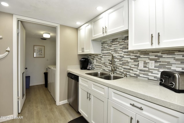 kitchen featuring washing machine and clothes dryer, white cabinetry, dishwasher, and sink