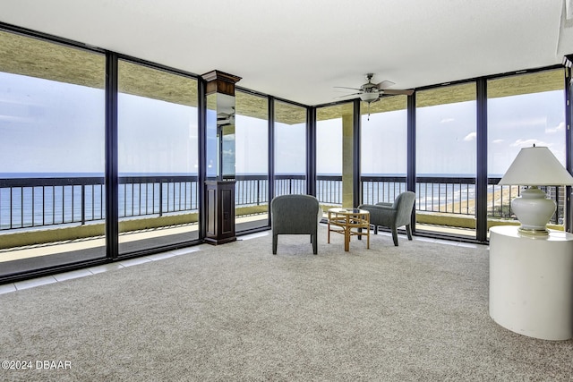 unfurnished sunroom featuring a water view, ceiling fan, and a healthy amount of sunlight