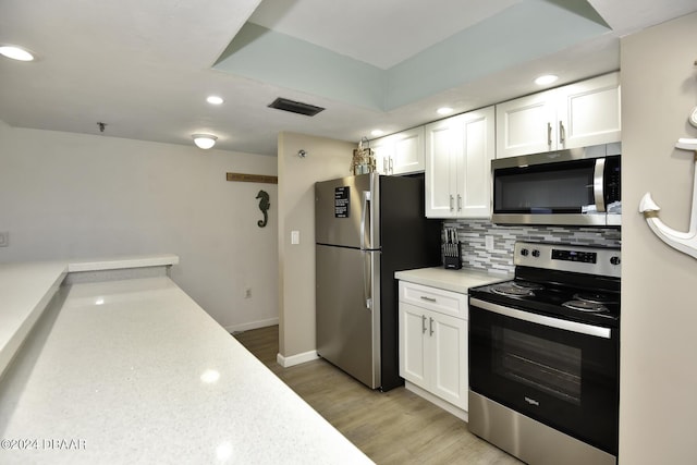 kitchen featuring appliances with stainless steel finishes, backsplash, light hardwood / wood-style flooring, and white cabinetry