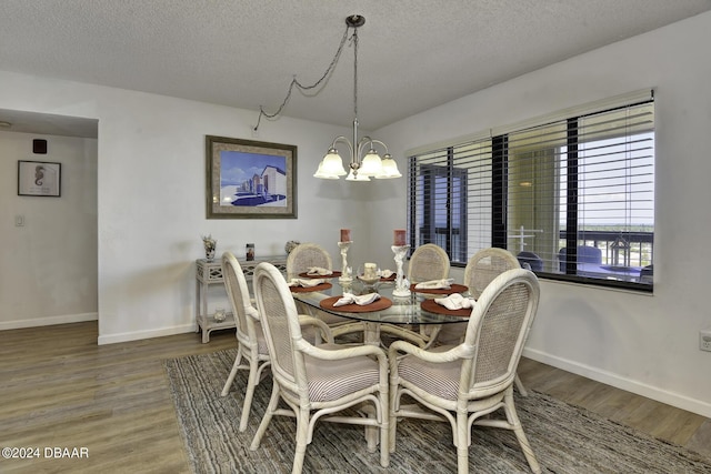 dining room with wood-type flooring, a textured ceiling, and an inviting chandelier