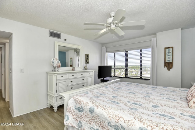 bedroom featuring ceiling fan, light hardwood / wood-style floors, and a textured ceiling