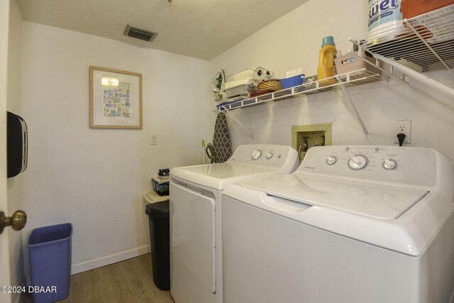 laundry area with hardwood / wood-style flooring and washing machine and dryer